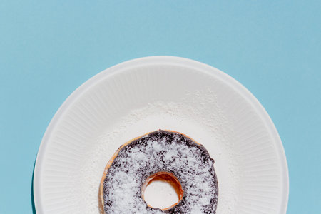Sweet dessert concept, Donut chocolate topping with icing in white plate on light blue background.の写真素材