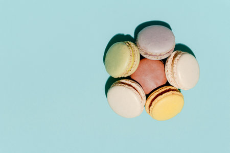 French dessert concept, Colorful macarons in pastel tones stacked on light blue background.の写真素材