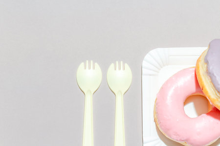 Sweet dessert concept, Delicious pastel donuts stacked in a plate with cutlery on a gray background.の写真素材