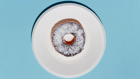 Sweet dessert concept, Donut chocolate topping with icing in white plate on light blue background.の写真素材