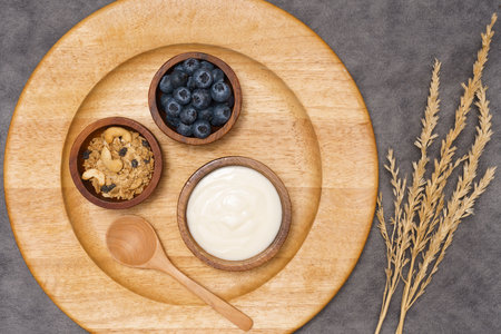 Healthy lifestyle concept, Greek yogurt fresh blueberry and granola in wood bowl on wooden plate.の写真素材