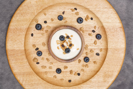 Healthy lifestyle concept, Yogurt in wood bowl topping with granola and blueberry served on plate.の写真素材