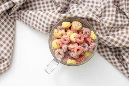 Healthy breakfast concept, Colorful ring cereal in glass cup with gingham cloth on white background.