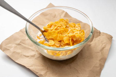Healthy food concept, Cornflakes and milk with spoon in bowl on brown paper for breakfast meal.