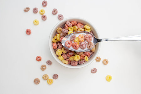 Breakfast cereal concept, Colorful ring cereals with milk in bowl and falling on white background.の写真素材