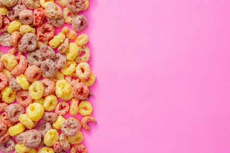 Breakfast cereal concept, Colorful ring cereals arranged in row on pink background.