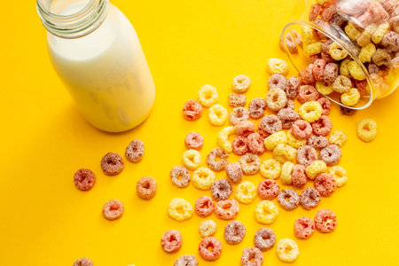 Breakfast cereal concept, Colorful ring cereals is poured out of glass jar and milk in bottle.の写真素材