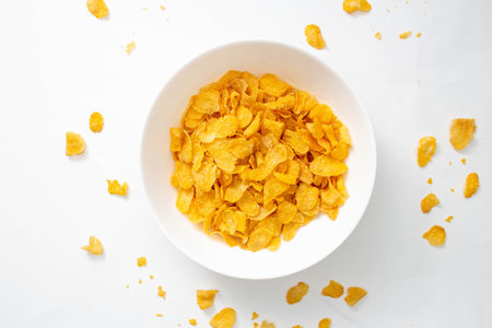 Healthy breakfast concept, Cornflakes in bowl and cornflakes fragments falling on white background.