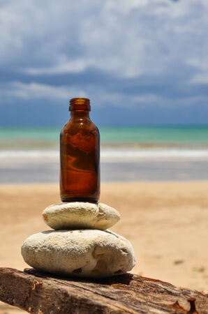 Stones and bottles at the beach with blue sky and cloudsの写真素材