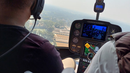 a man wearing a black shirt and headphones sits in the cockpit of a helicopter, looking out the...
