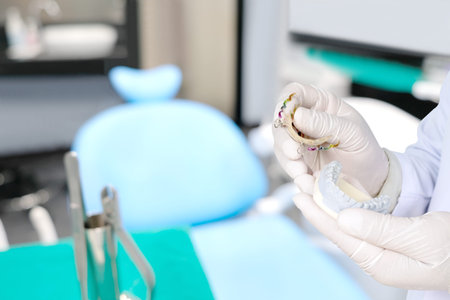 Dentist show dental retainer orthodontic appliance in his hand / in office or clinic.