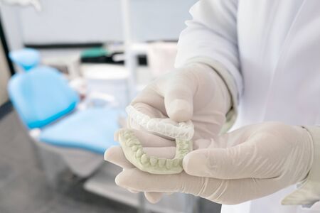 Dentist show dental retainer orthodontic appliance in his hand, in office or clinic.の写真素材