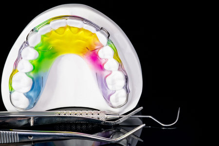 Close up; Dental retainer orthodontic appliance and dental tools on the black background.