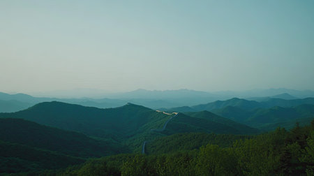 A breathtaking view of serene mountains under soft mist with a winding road weaving through lush greenery, evoking tranquility and natural beauty.の素材