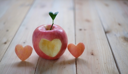 Red apple with a heart shaped cut-out on wood background. Healthy eating.の写真素材