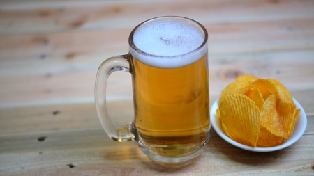 Glass tankard with lager beer and potato chip on an old wooden planksの写真素材
