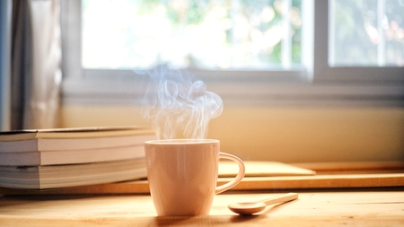 This morning a cup of hot coffee smoke and a book on wood table with window background.の写真素材