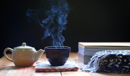 hot tea in teapot and cup on wood table, black background. Winter tea time.の写真素材