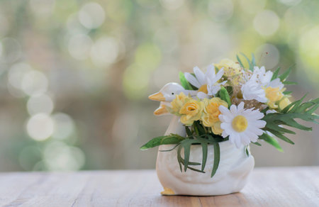 Artificial flowers in a vase on wood and background bokeh.の写真素材