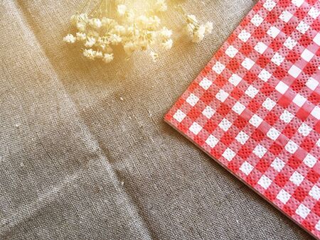 Red and white napkin and small flowers on burlap tableclothの写真素材