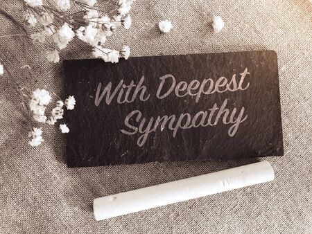 "With deepest sympathy" note with flowers on small chalk board backgroundの写真素材