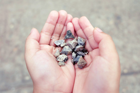little girl hands holding small stonesの写真素材