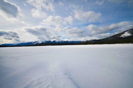 frozen lake and mountains covered with snow in National Parkの写真素材