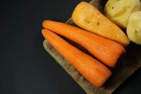 Raw peeled carrots and potatoes isolated on dark/black backgroundの写真素材