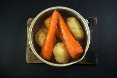 Raw peeled carrots and potatoes on water. isolated on black/dark backgroundの写真素材