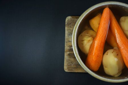 Raw peeled carrots and potatoes on water. isolated on black/dark backgroundの写真素材