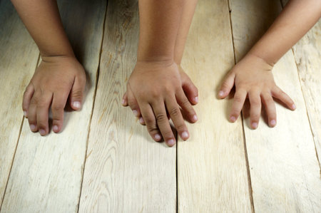Children's hands on wooden table.