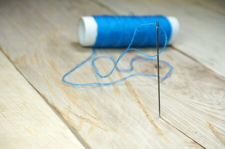 Blue threads and sewing needles on the wooden table. Selective focus to sewing needleの写真素材