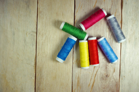 Top view colorful spools of thread on wooden table