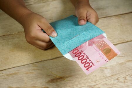 Hand of young kid holding indonesian money. Rupiah/IDR money.の写真素材