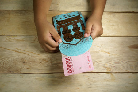 Hand of young kid holding indonesian money. Rupiah/IDR money.