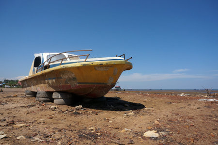 Old abandoned wrecked speed boat at ship or boat graveyard. Lots of different dry docked.の写真素材