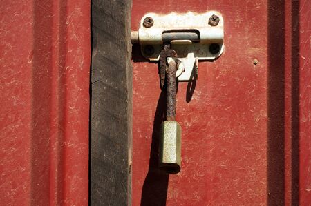 Rusty padlock on red metal door.の写真素材
