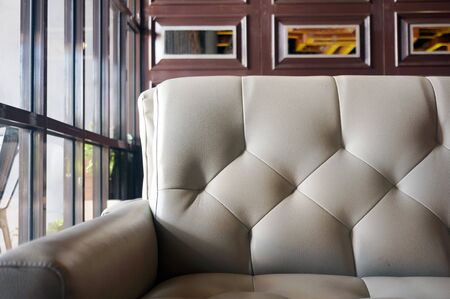 Modern gray leather sofa with grunge brown & glass wall in coffee shop.の写真素材