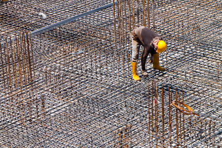 A worker is doing a final inspection of the floor reinforcement