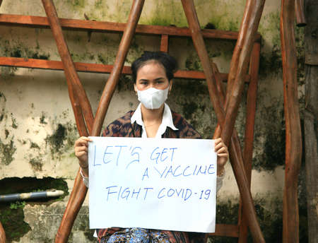 a girl holds a banner that says Let's Get a Vaccine Fight Covid-19 to invite the public to care and help eradication of the covid-19のeditorial素材