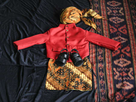 a set of traditional clothing from Central Java Indonesia consisting of a shirt, pants, a blangkon hat and sandals.の写真素材