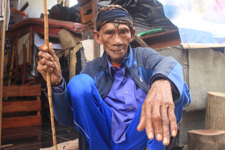 Close-up photo of an old man from Indonesia wearing a traditional hat.