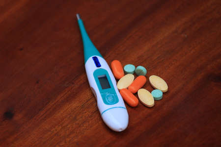 During the COVID-19 pandemic, always prepare medical equipment and medicines. Photo of thermometer and pills for pain medicine.の写真素材