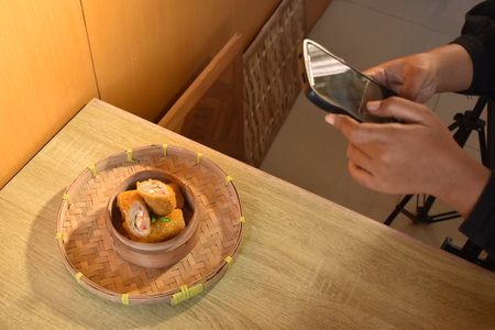 Woman take a photo of food with smart phone in restaurant.の写真素材