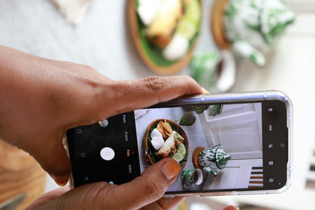 Woman taking photo of breakfast with smartphone, closeup. Food blogger conceptの写真素材