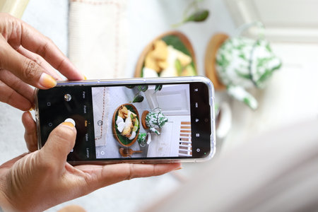 Woman taking photo of breakfast with smartphone in the morning at home.の写真素材