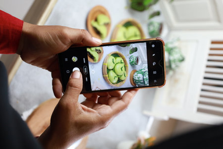 Woman taking a photo of kiwi fruit with smart phone.の写真素材