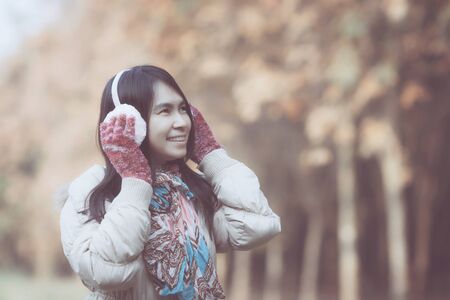 beautiful woman wearing winter clothing and blur backgroundTrees with brown leavesの写真素材
