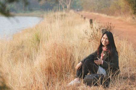 Happiness woman enjoy sit in the sundown  time at grassland. Rim reservoir with vintage color tone effectの写真素材