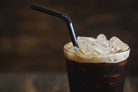 Iced coffee in glass with cream and wood backgroundの写真素材